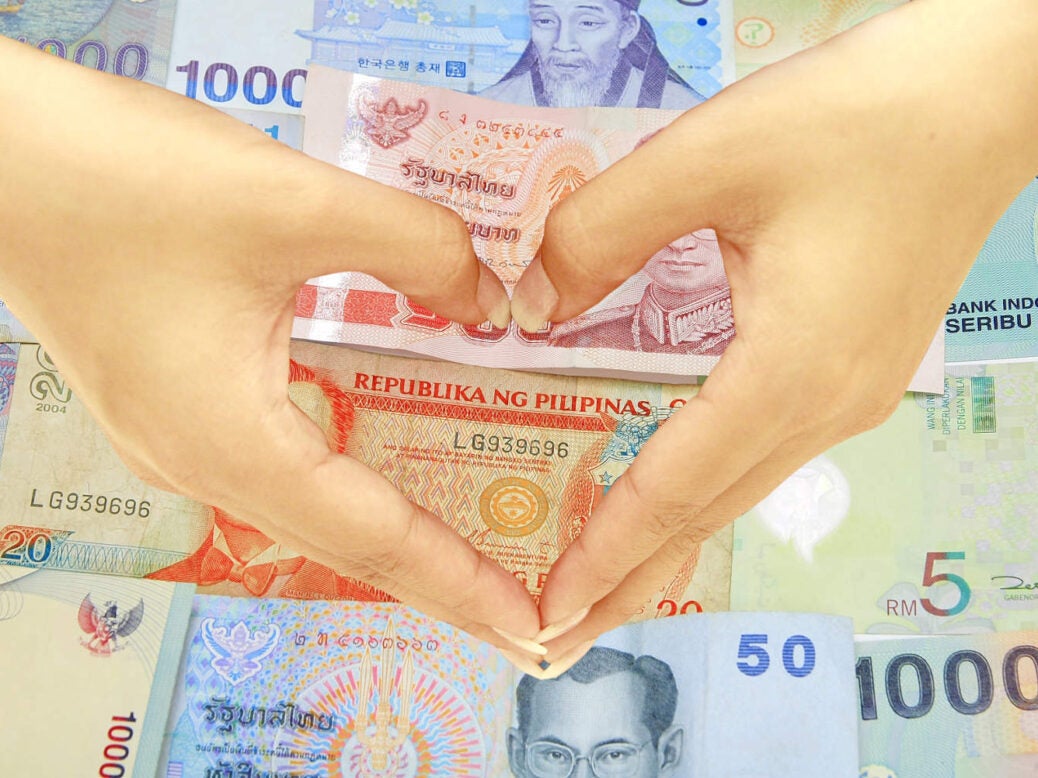 Hands making a heart over various currencies for Valentine's Day