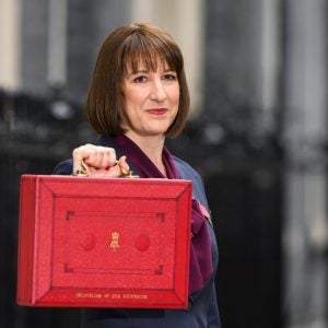 A Photo Of Uk Chancellor Rachel Reeves Holding Aloft Her Red Ministerial Box, Used To Illustrate An Op-ed About Uk Ai.